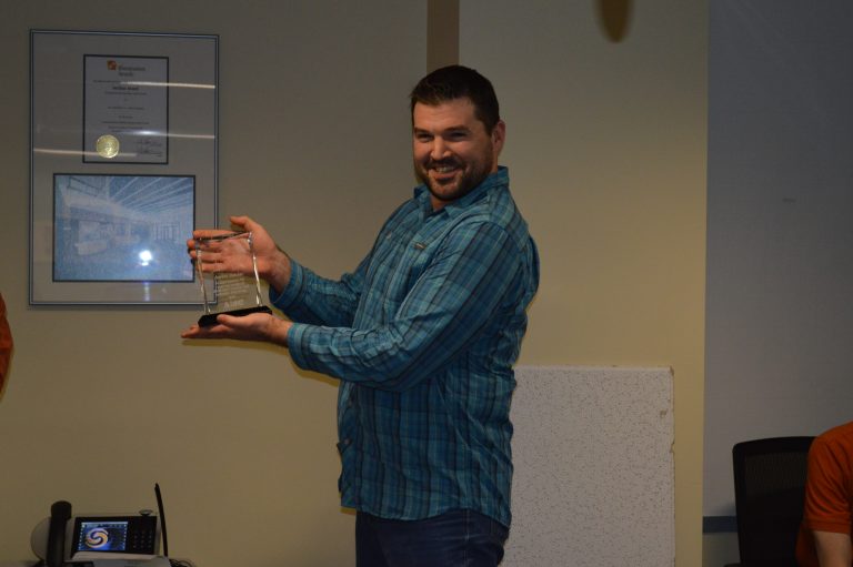 Aaron holding an award and smiling