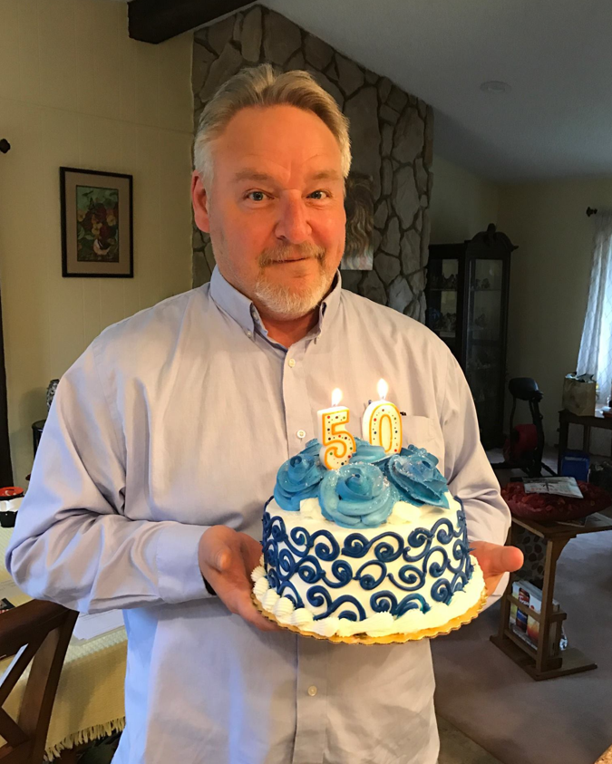 Keith Confer holding cake on his 50th birthday