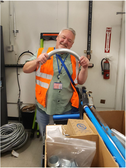 Keith holding metal pieces of machinery