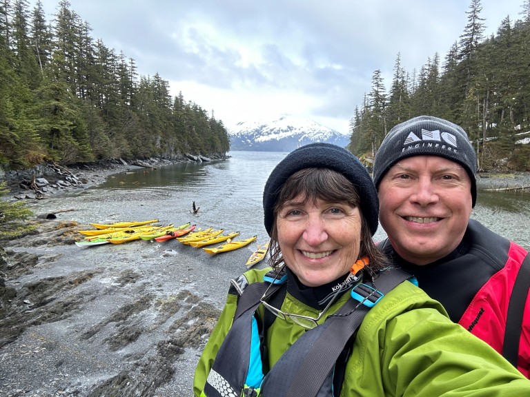 Ken Ratcliffe with woman on coast with kayaks