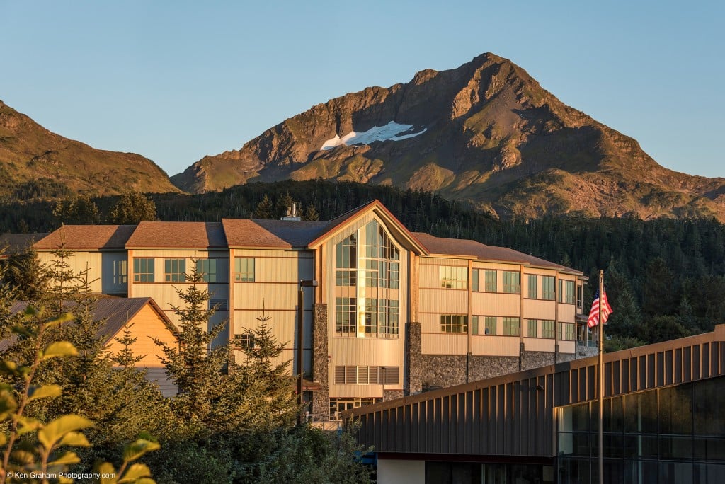 Large wood panelled building nestled in wooded mountains