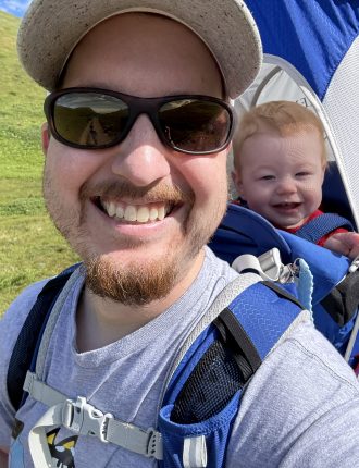 Christian with a baby in a carrier on his back