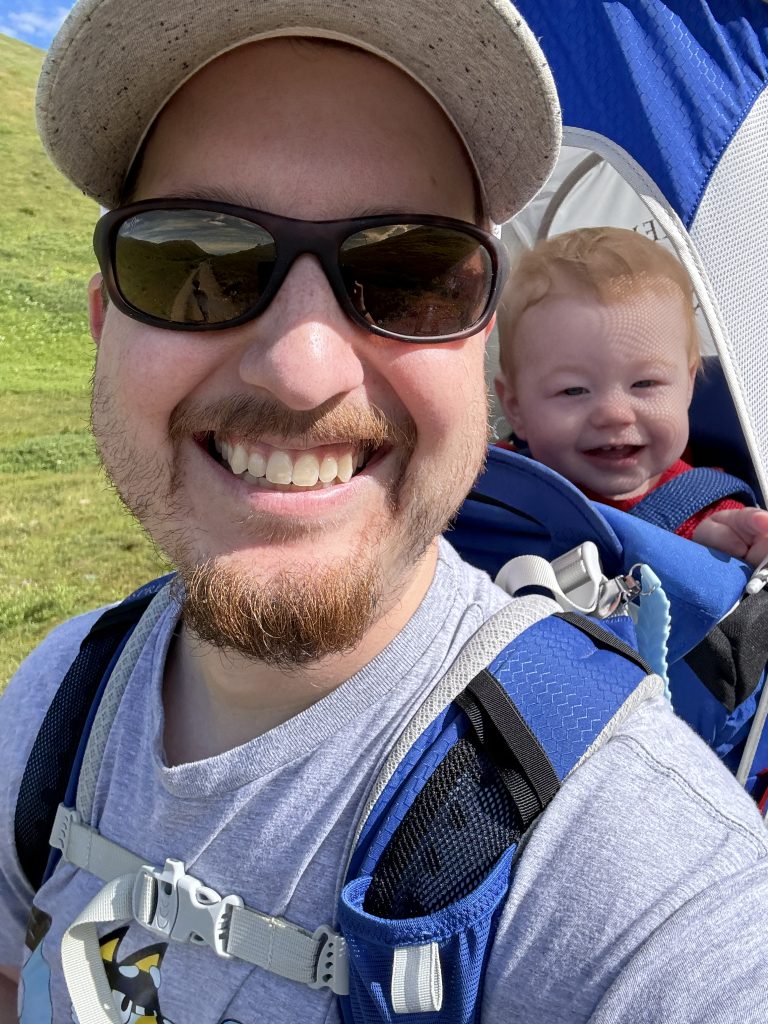 Christian with a baby in a carrier on his back