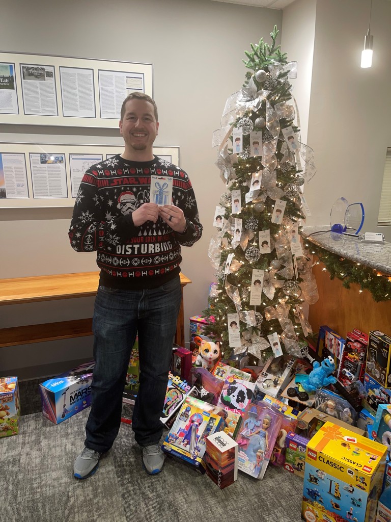 Christian holding a gift card in front of a Christmas tree