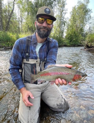 Cory Crawford holding a fish in a creek