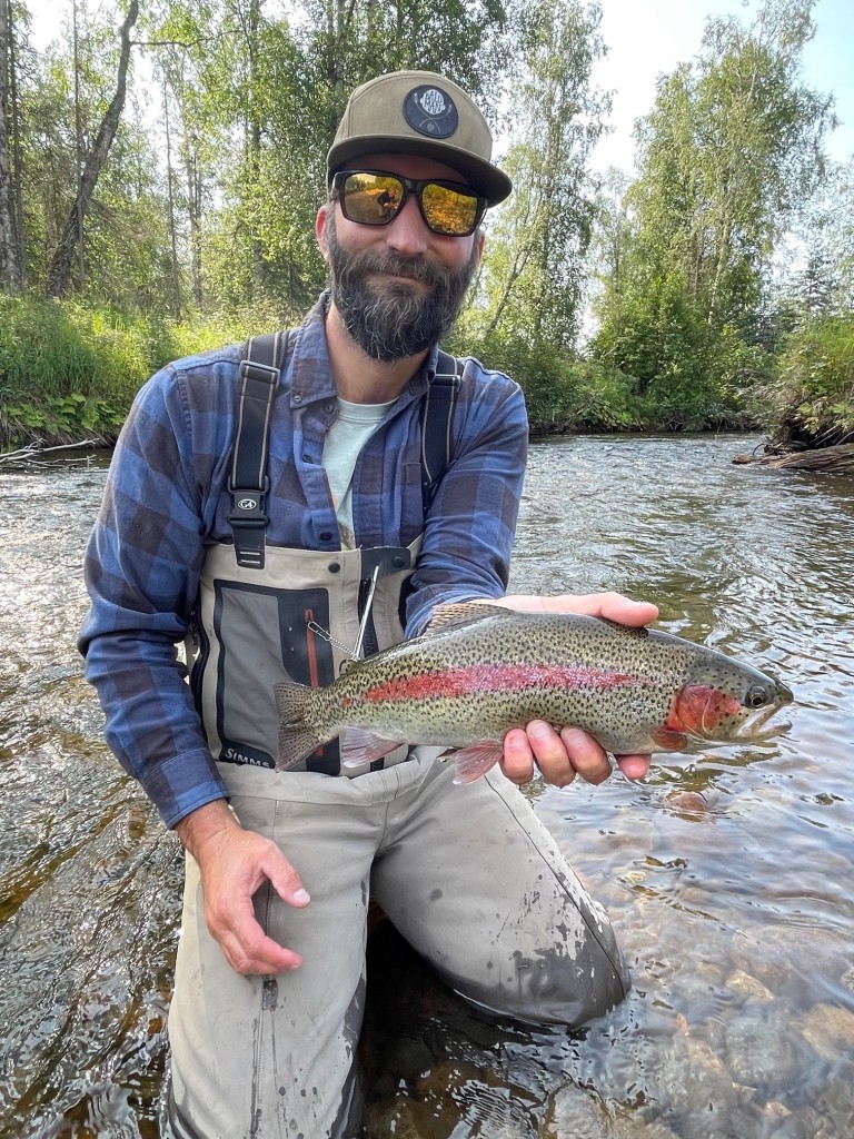 Cory Crawford holding a fish in a creek