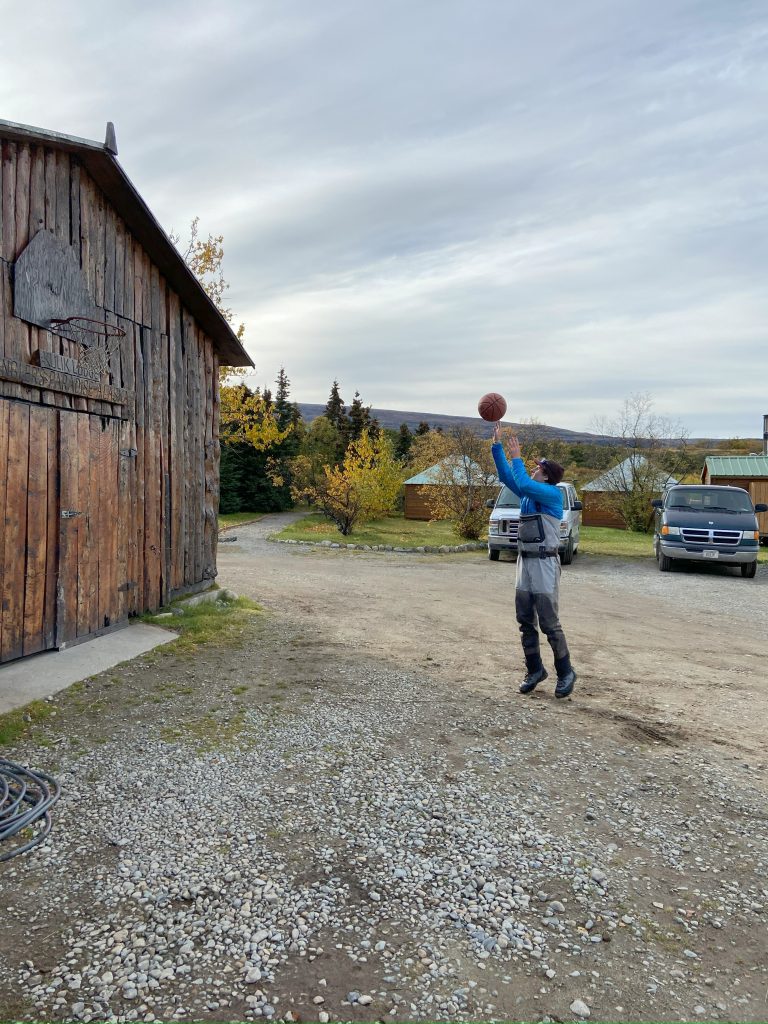 Dylan playing basketball with a hoop on a worn out barn
