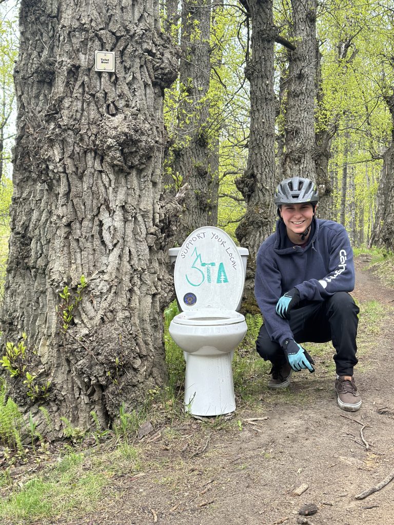 Man posing next to toilet on a trail