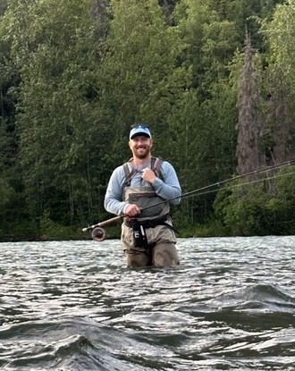 Derek holding a fishing rod in the water
