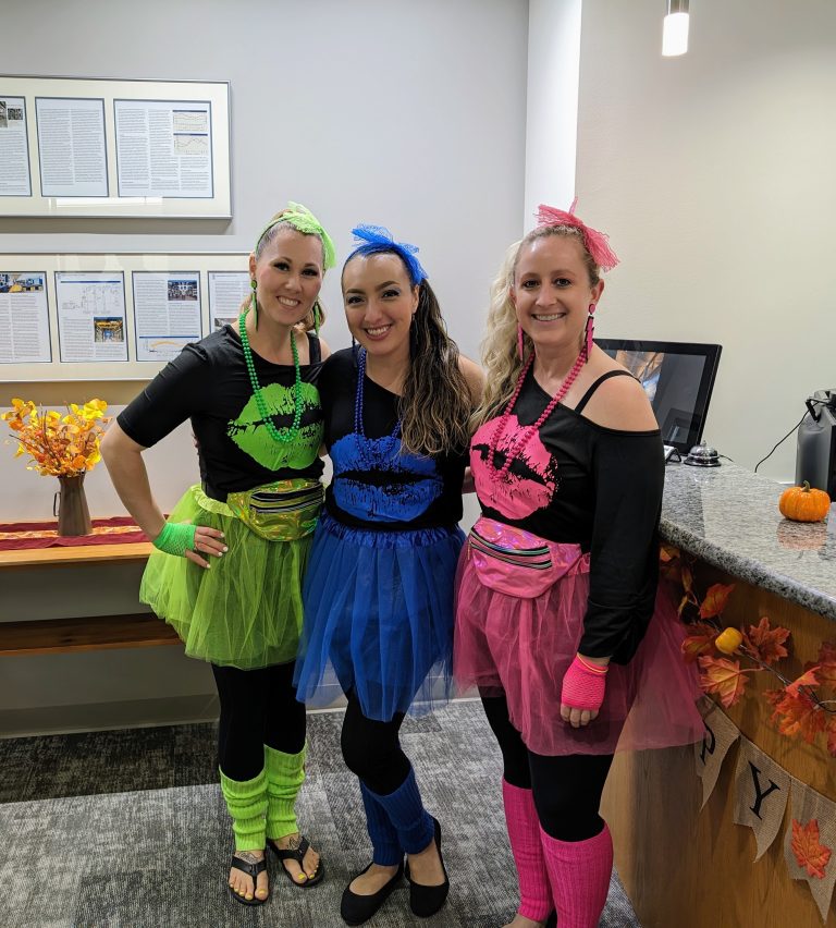 Michelle posing with two other AMC employees in an 80s neon costume