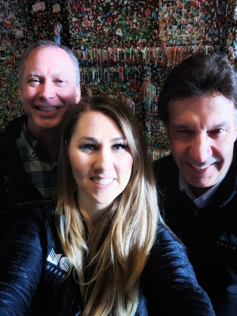 Michelle with two other AMC employees standing in front of a wall covered in gum