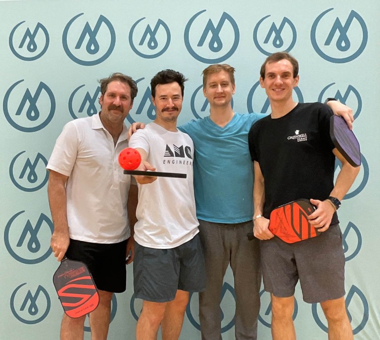 Four men playing pickleball