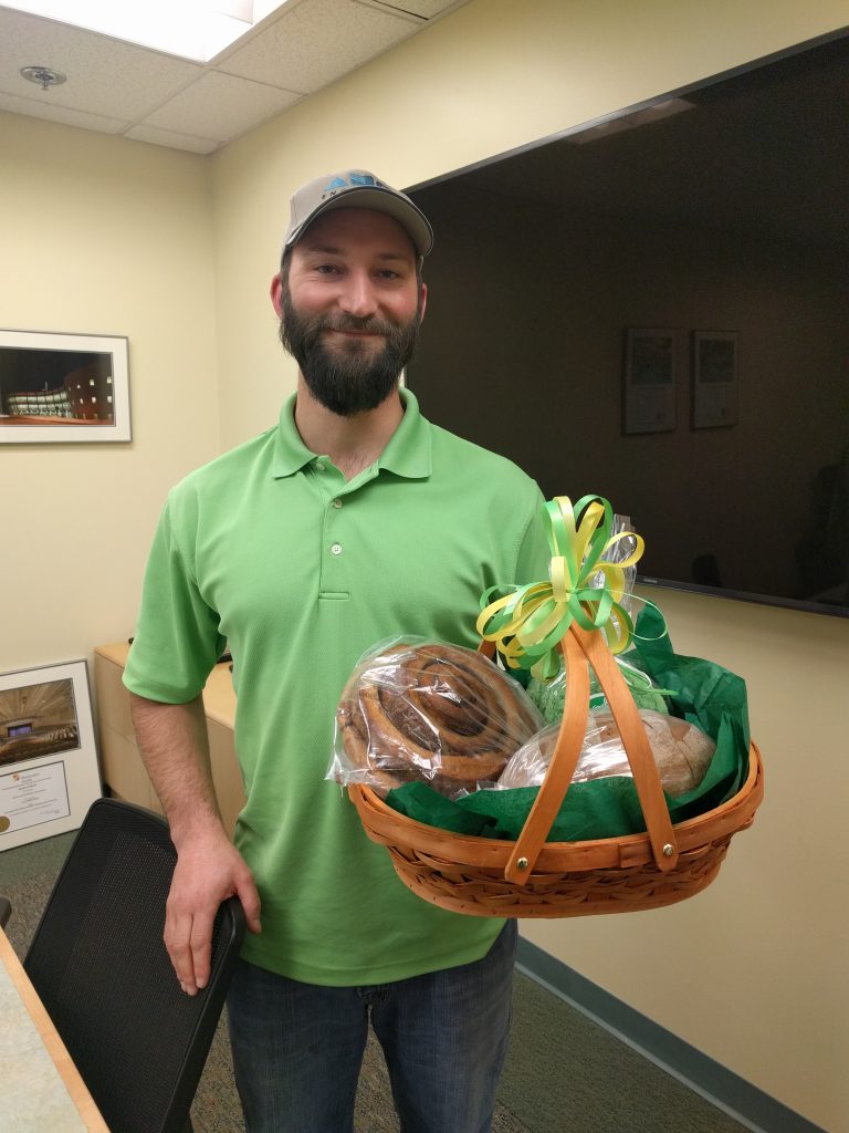 Cory holding a gift basket with large baked goods
