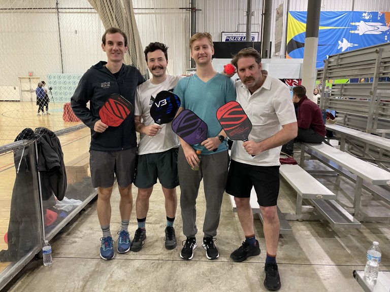 Four men playing pickleball