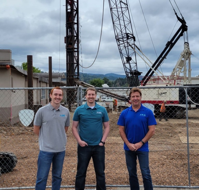 Kyle and other AMC employees standing in front of large construction equipment