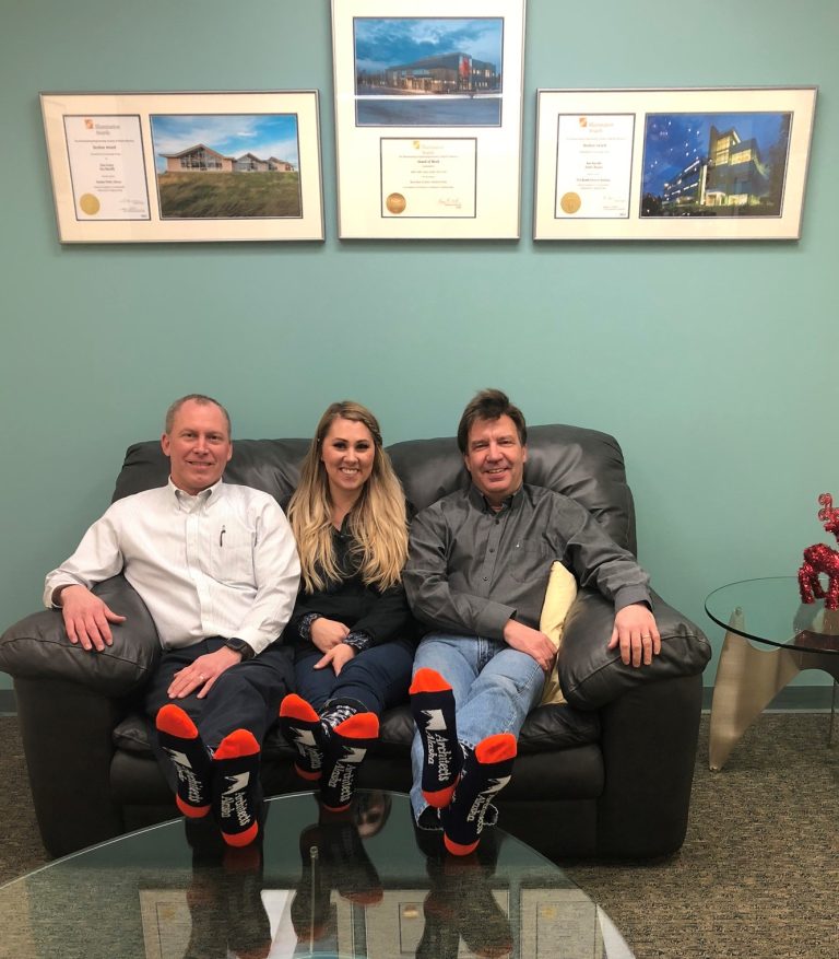 Michelle sitting on a couch with two other AMC employees in matching socks