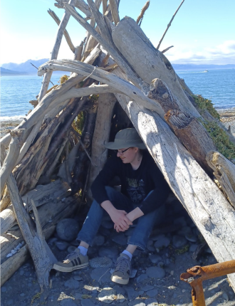 Nolan sitting in small wooden tipi