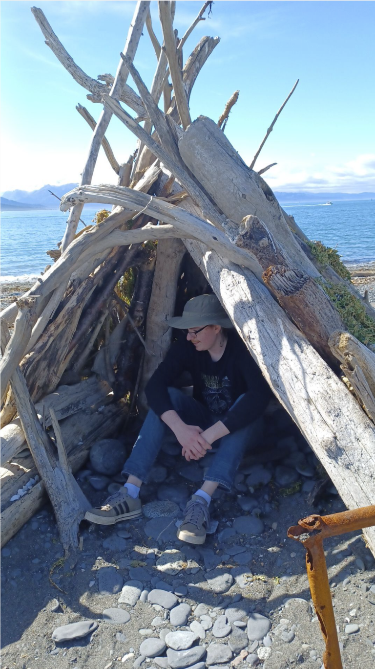 Nolan sitting in small wooden tipi
