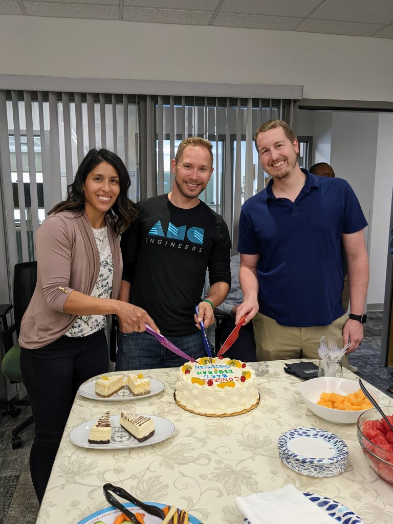 Multiple AMC employees cutting a cake at a company event