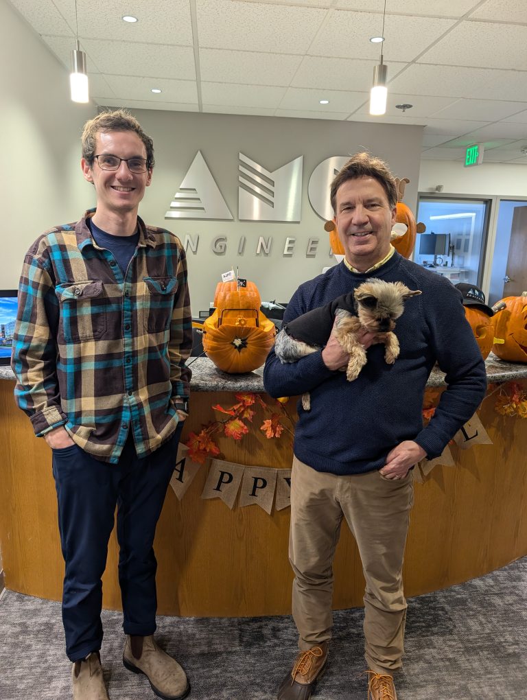 Dylan and another AMC employee posing in front of a pumpkin carved like a pirate ship at a pumpkin carving competition