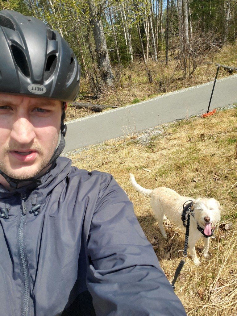 Sam Berdahl biking a trail with a dog