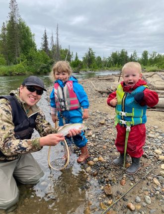 Trenton posing with a fish and two children in life vests
