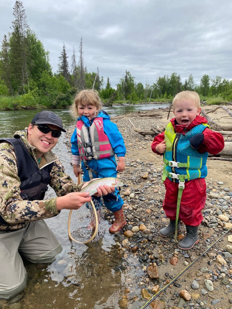 Trenton posing with a fish and two children in life vests