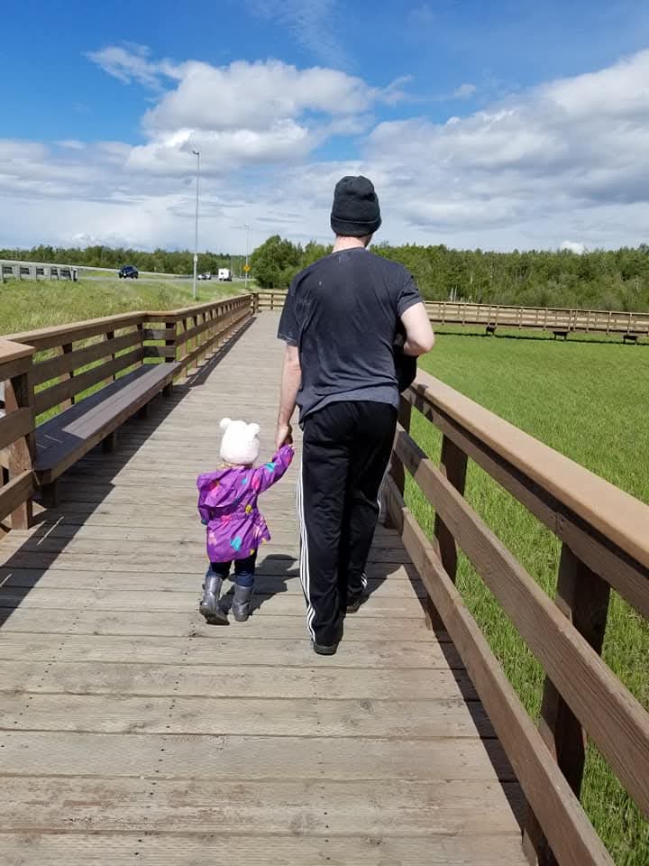 Man walking down elevated wooden trail with young girl