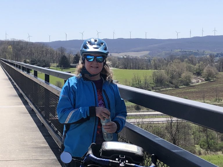 Tami riding a bike along a bridge