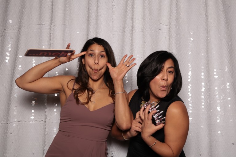 Deborah with a woman making silly faces in front of a backdrop with props