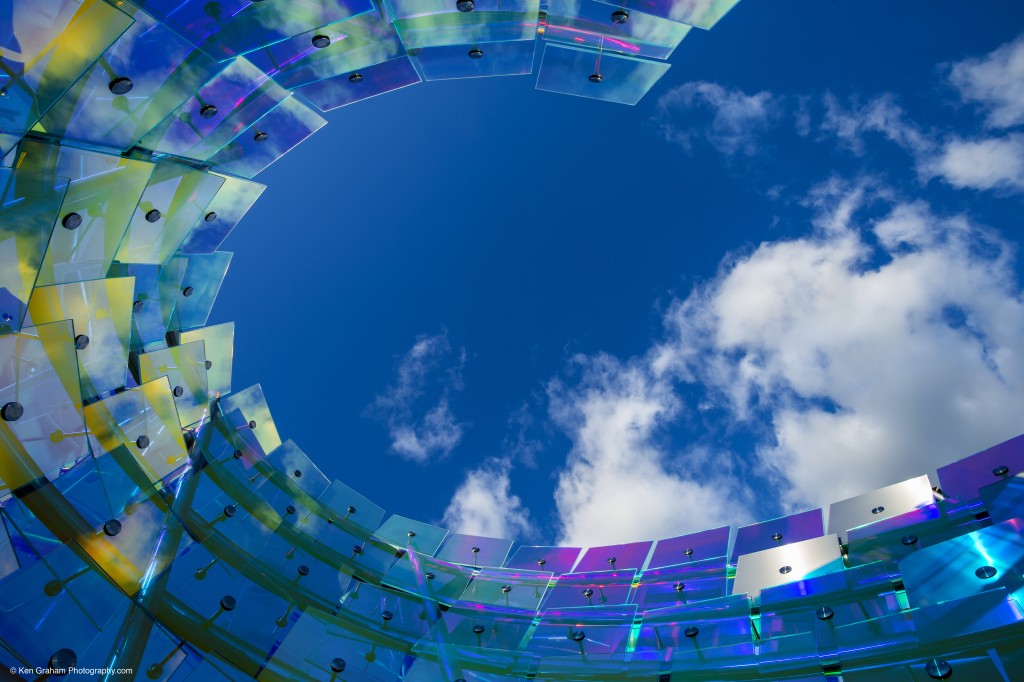 Fragmenta by artist Osman Akan. Sculputre made of iridescent glass panels curved in a circle.