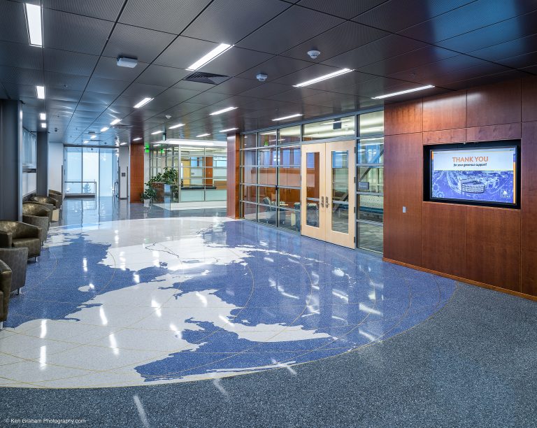 Brightly lit entryway with tiles on the floor shaped like the earth focused on Alaska