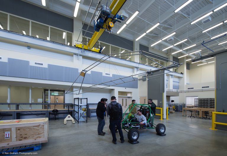 Large workshop with framed car and metal wireframe hanging from ceiling