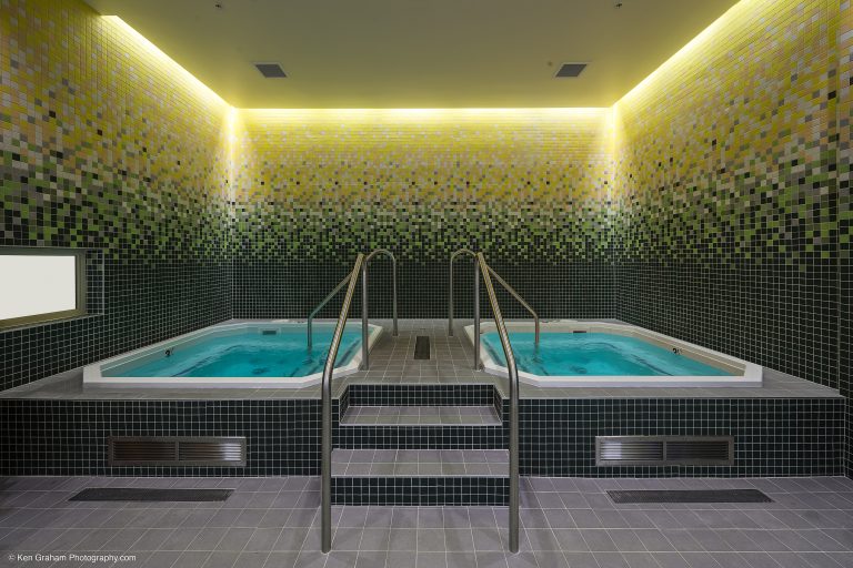 Two hot tubs with decorative lighting and tiled walls and floors