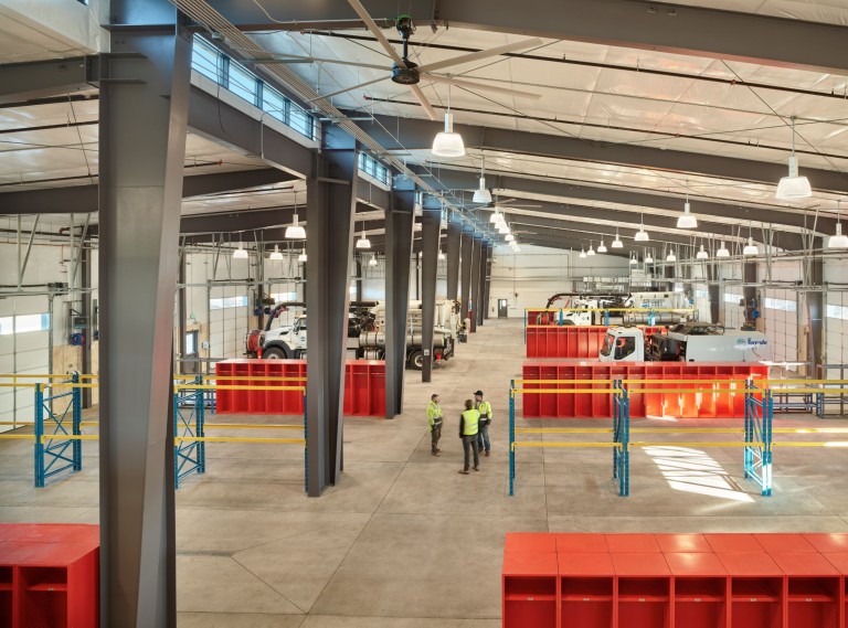 Large warehouse with many garage doors, vehicles, and storage
