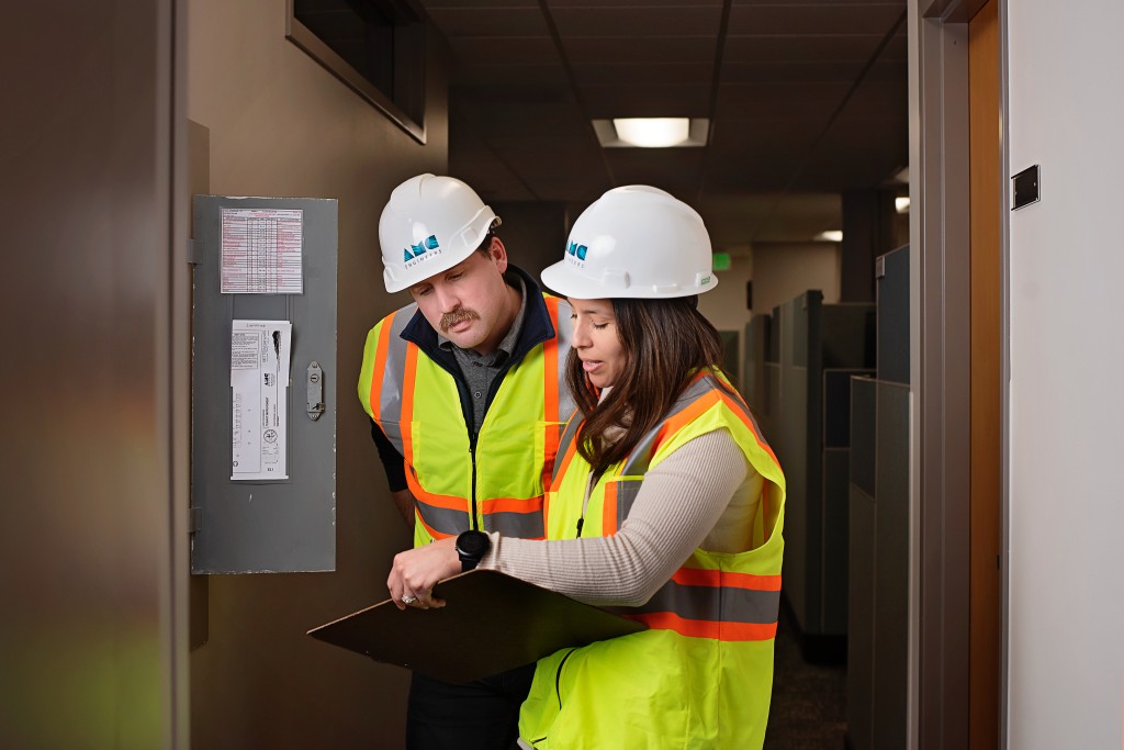 Two AMC employees looking at electrical panel