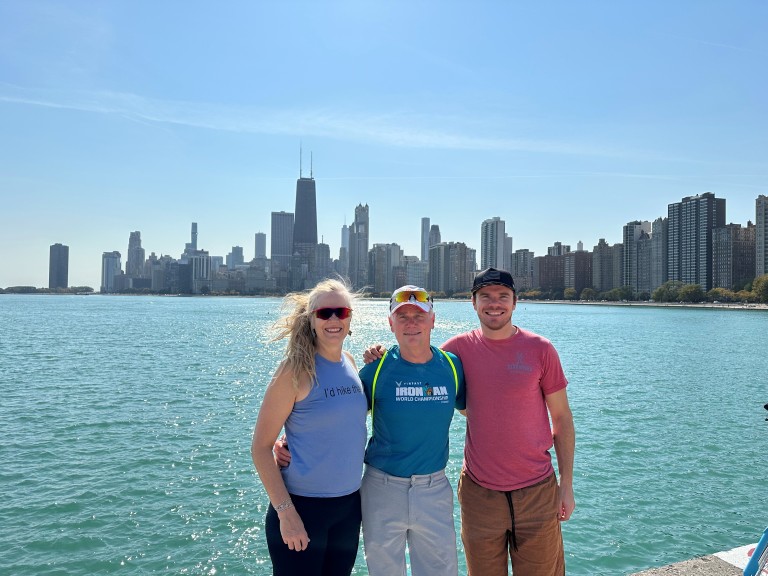 Jake Kirk posing with older couple in front of city skyline