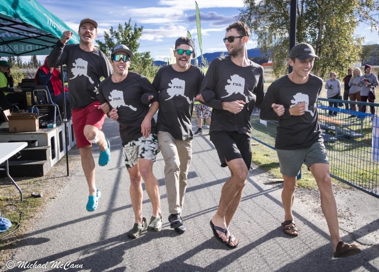 Jake Kirk hooking arms with multiple men in running relay event