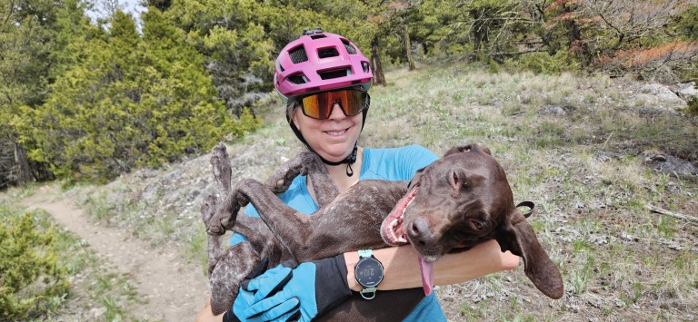 Brown dog being held by woman in a helmet