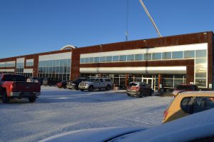 Wide multistory building with large windows and a crane overhead