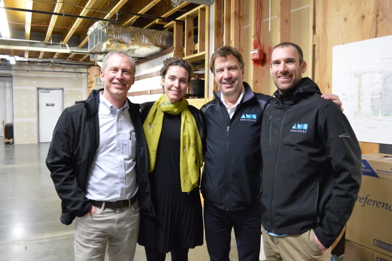 Multiple AMC employees posing together in unfinished basement