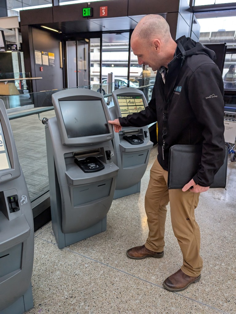 EMC employee looking at ticket machine in airport