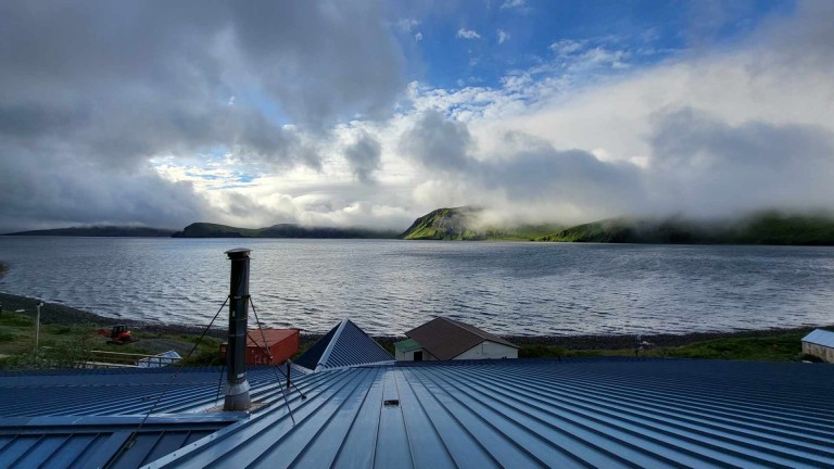 Buildings along lake with mountainscape and clouds