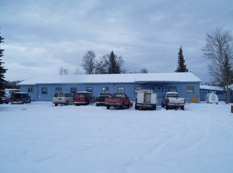 Blue slab building and cars parked in deep snow