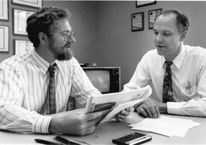 Old black and white photograph of two men looking at papers